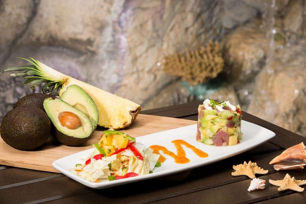 Seafood platter featuring fish fillets, avocados, and dipping sauce.