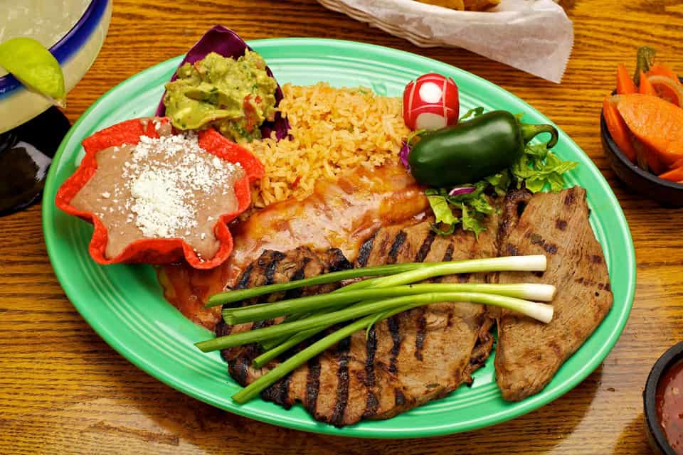 Traditional Mexican dish served with rice, beans, and garnishes on a colorful plate